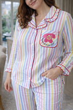 Person wearing a colorful striped pajama set with a pink phone design on a blurred indoor background